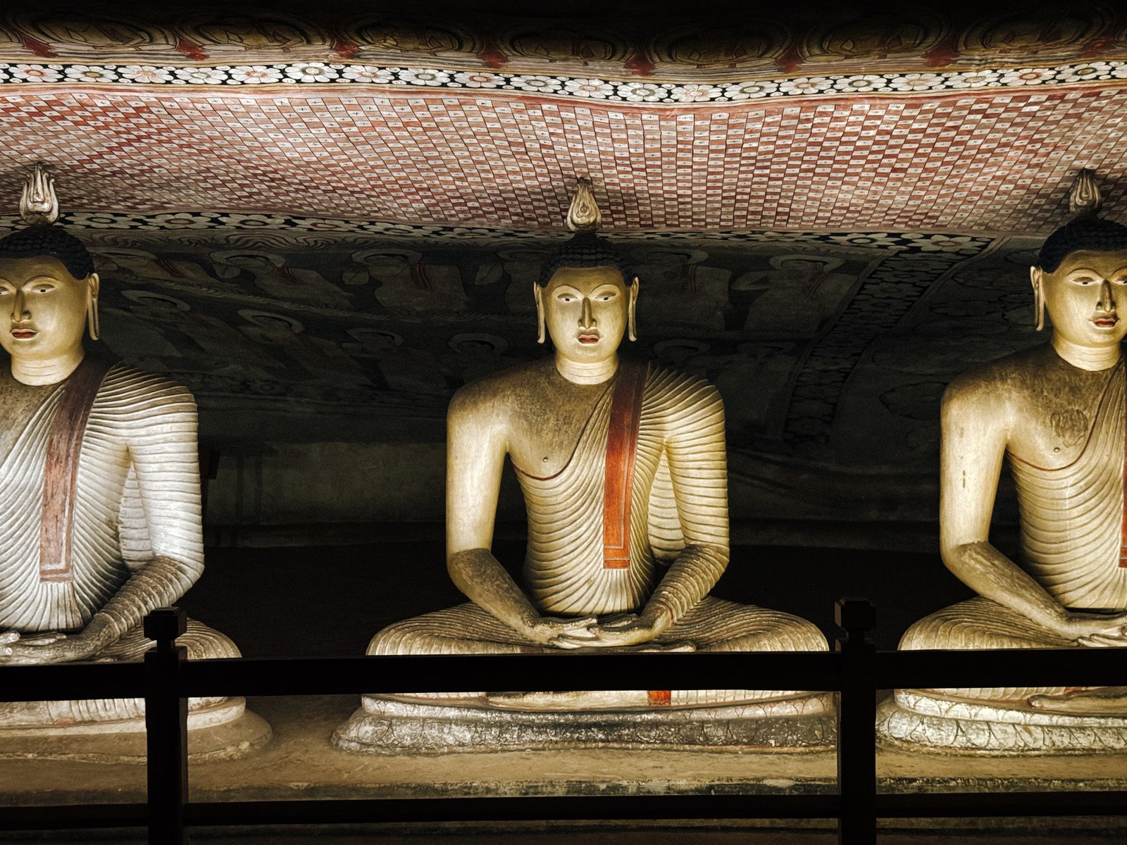 Dambulla cave temple - illuminated Buddha statues and painted murals inside the caves